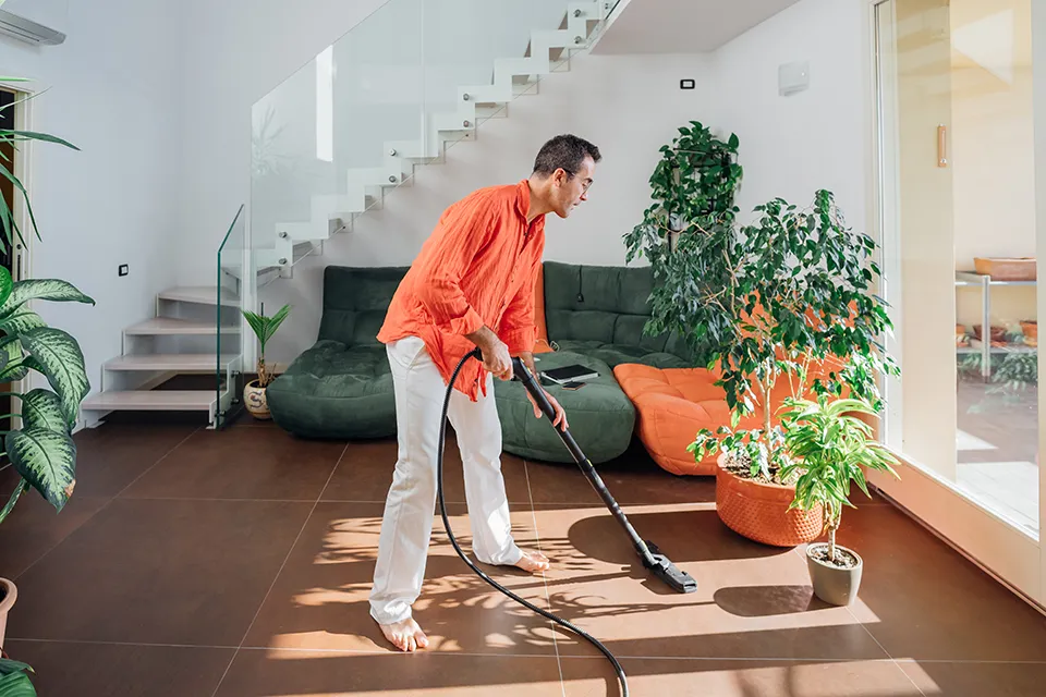 A man vacuuming the floor in a home